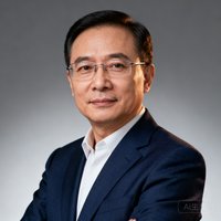 一位穿着深蓝色西装、戴着无框眼镜的中年商务男士半身肖像照，背景为柔和的灰色渐变，表情沉稳自信。
